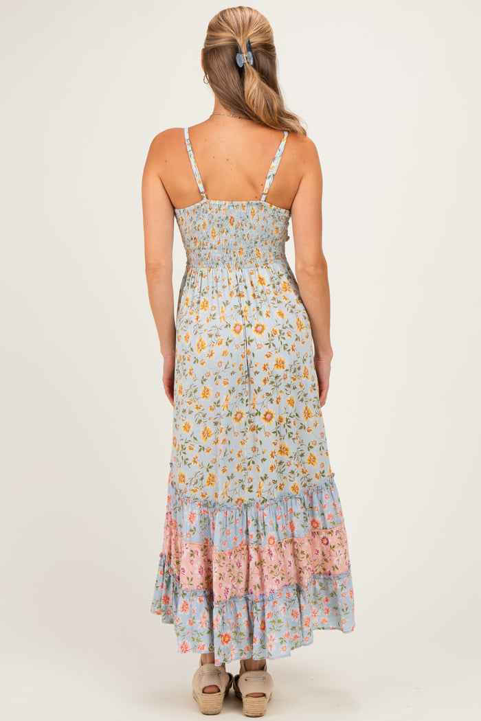 woman wearing a blue floral maxi dress with a smocked back and tiered hem, shown from the back