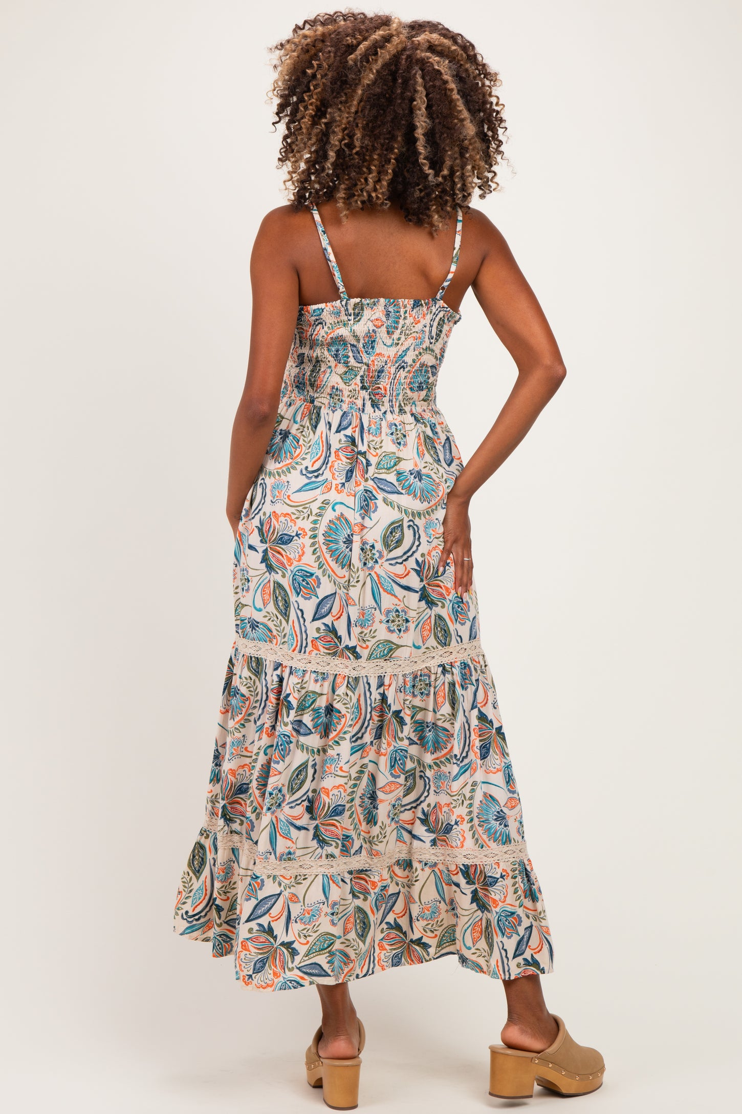 woman wearing a floral print maternity maxi dress with smocked bodice and tiered skirt, showing her back
