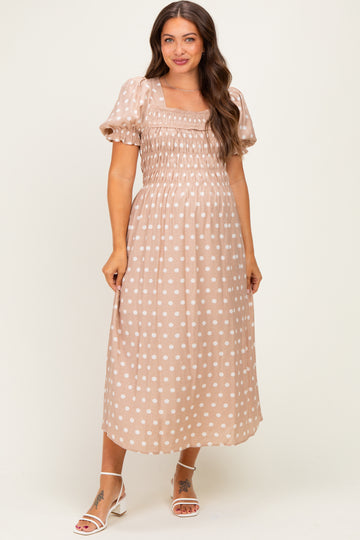 woman wearing a polka dot maternity dress with puff sleeves and a fitted bodice, smiling against a neutral background