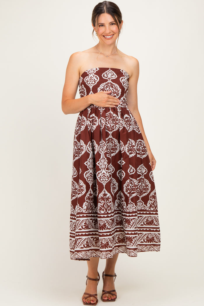 woman wearing a brown strapless maternity maxi dress with white floral patterns and holding her baby bump