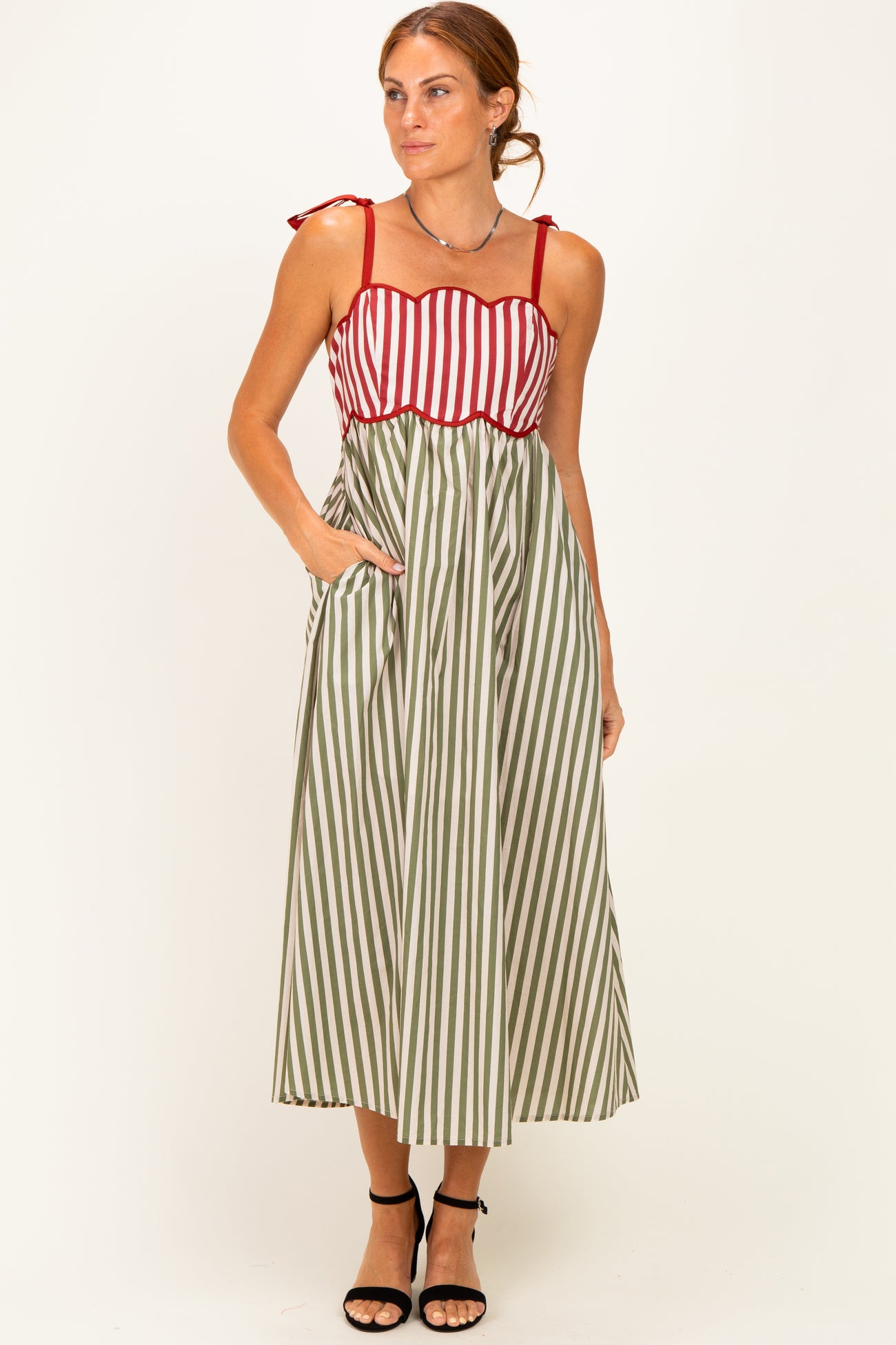 woman wearing a red and white striped maxi dress with green stripes, featuring tie straps and pockets
