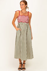 woman wearing a red and white striped maxi dress with green stripes, featuring tie straps and pockets
