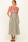 woman wearing a red and white striped maxi dress with green stripes, featuring tie straps and pockets