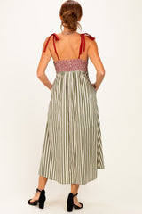 woman wearing a back view of a green and white striped maxi dress with red tie straps and smocked bodice