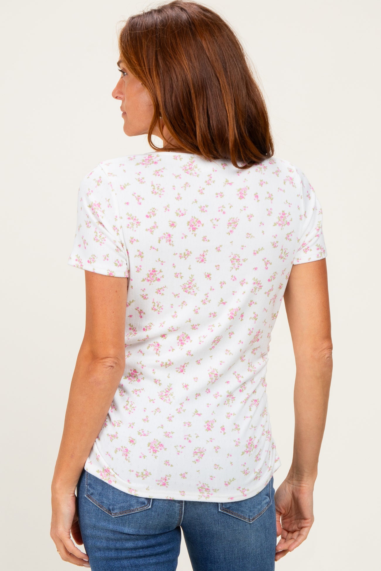 woman wearing a white short sleeve top with a pink floral print, viewed from the back