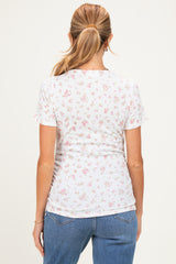 woman wearing a floral print white maternity top, view from the back with short sleeves and a fitted style