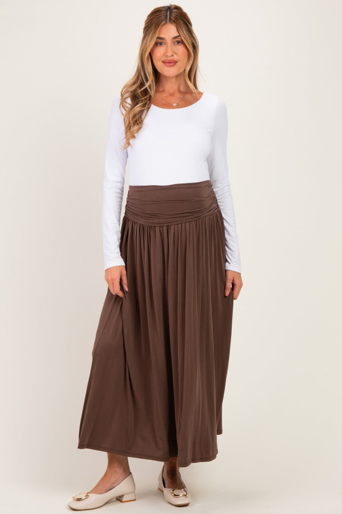 woman wearing a white long sleeve top and a brown maxi skirt, showcasing a flattering maternity style