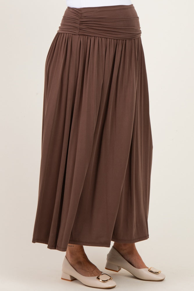 woman wearing a brown maternity maxi skirt with a ruched waistband and flowing fabric