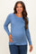 woman wearing a light blue long sleeve maternity top and showing her baby bump