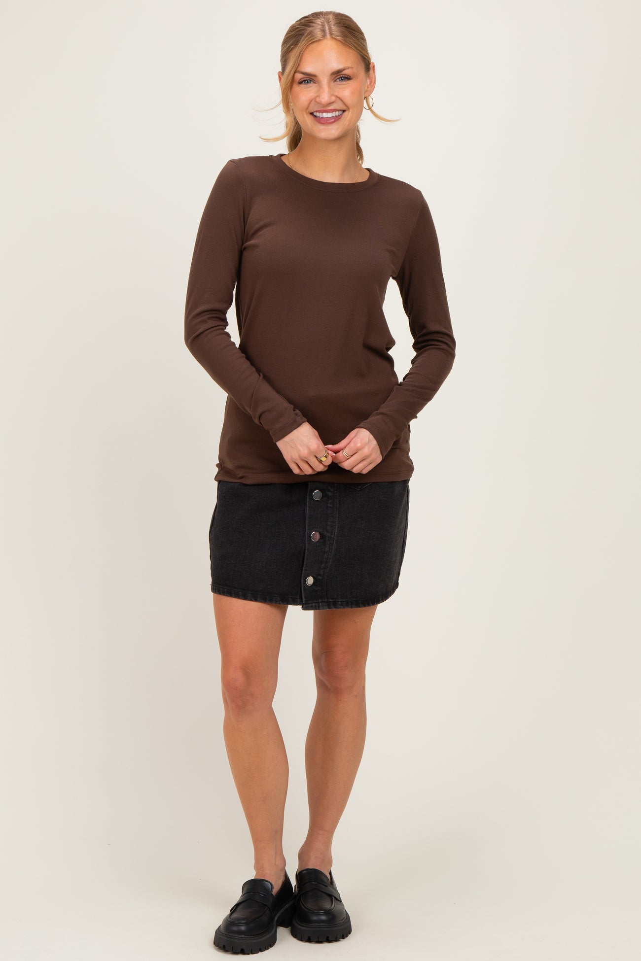 woman wearing a brown long sleeve top and a black denim button-up skirt