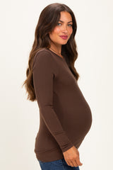 woman wearing a brown long sleeve maternity top and showcasing her baby bump