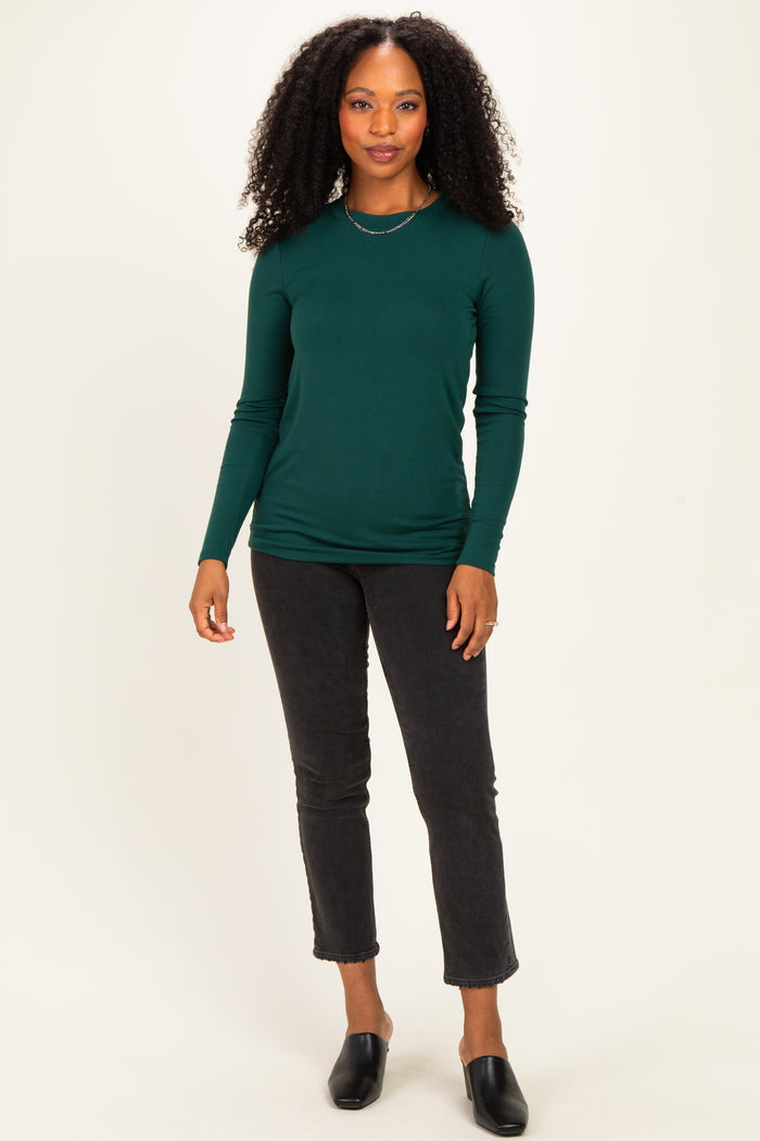 woman wearing a dark green long sleeve fitted top paired with black cropped jeans and slide-on mules