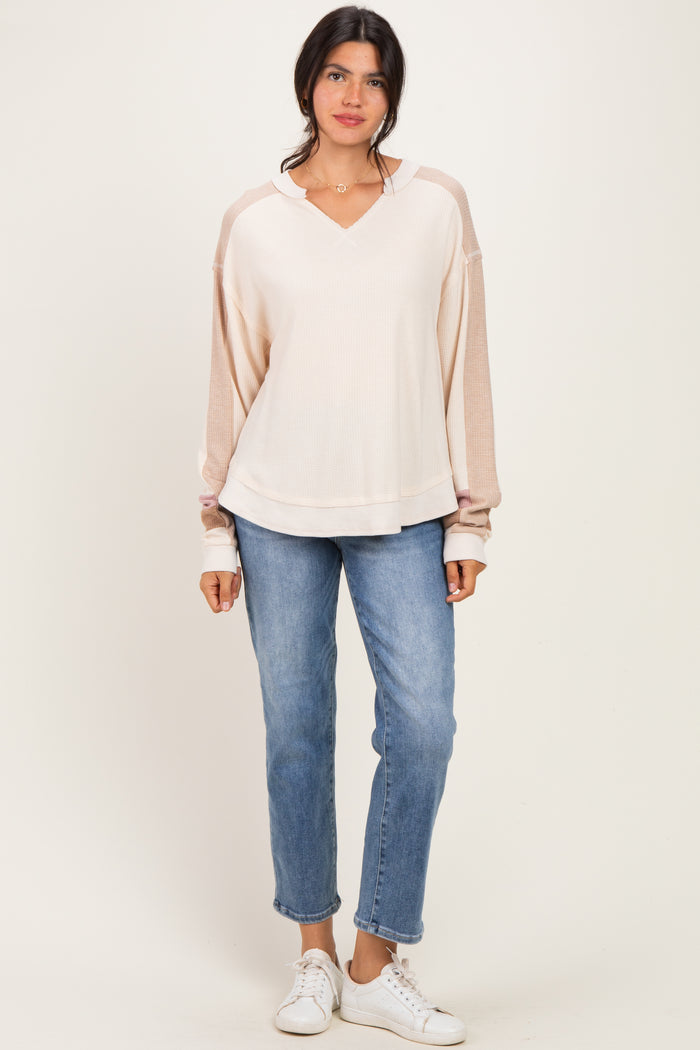 woman wearing a light pink long sleeve hoodie paired with blue jeans and white sneakers