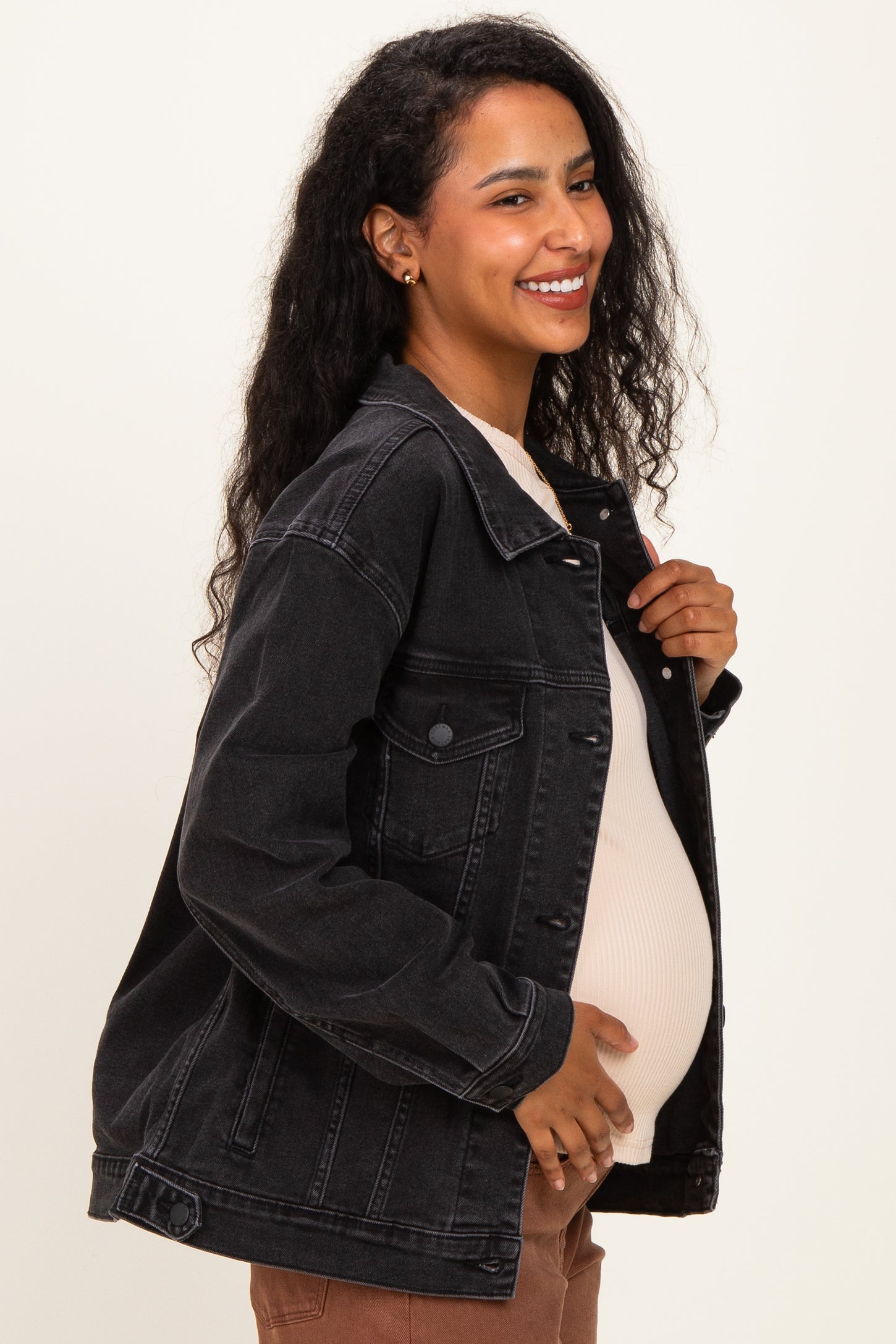 woman wearing a black denim maternity jacket and holding her baby bump