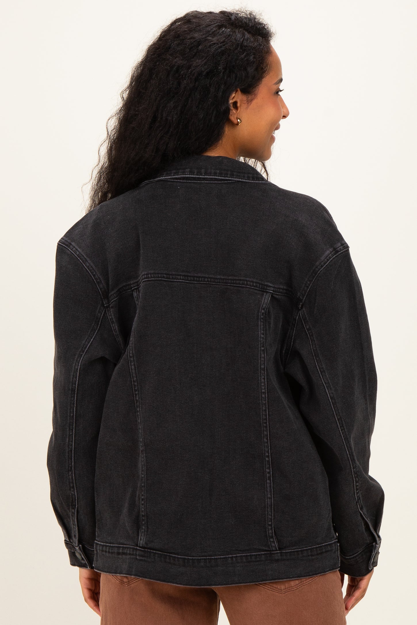 woman wearing a black denim maternity jacket, shown from the back with loose fit and dropped shoulders