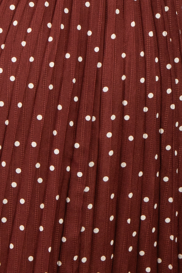 maternity wear in a rust-colored dress with white polka dots and pleated details