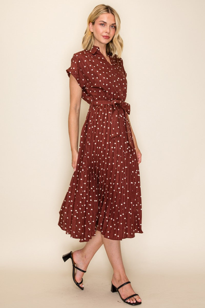 woman wearing a maroon short sleeve shirt dress with white polka dots and a tie waist detail, styled with black sandals