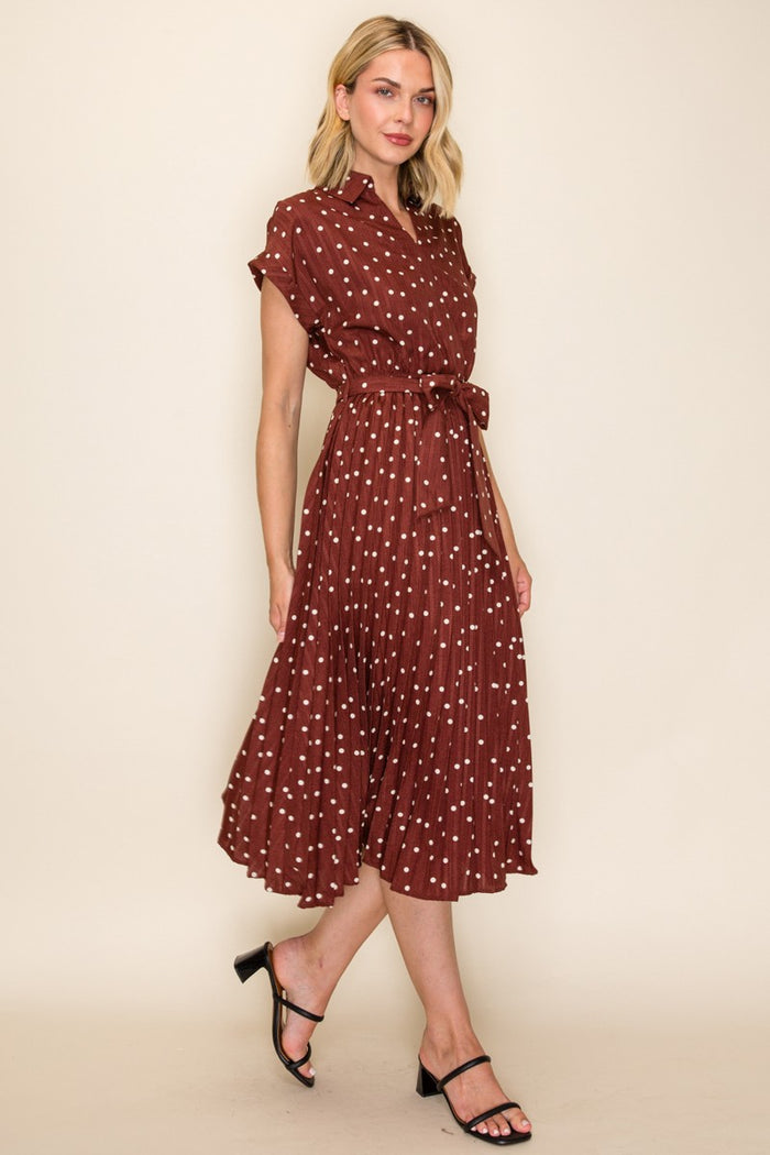 woman wearing a maroon short sleeve shirt dress with white polka dots and a tie waist detail, styled with black sandals