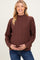 woman wearing a brown cable knit maternity sweater and holding her baby bump