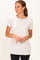woman wearing a light beige short sleeve top with a rounded neckline and a relaxed fit, paired with black leggings