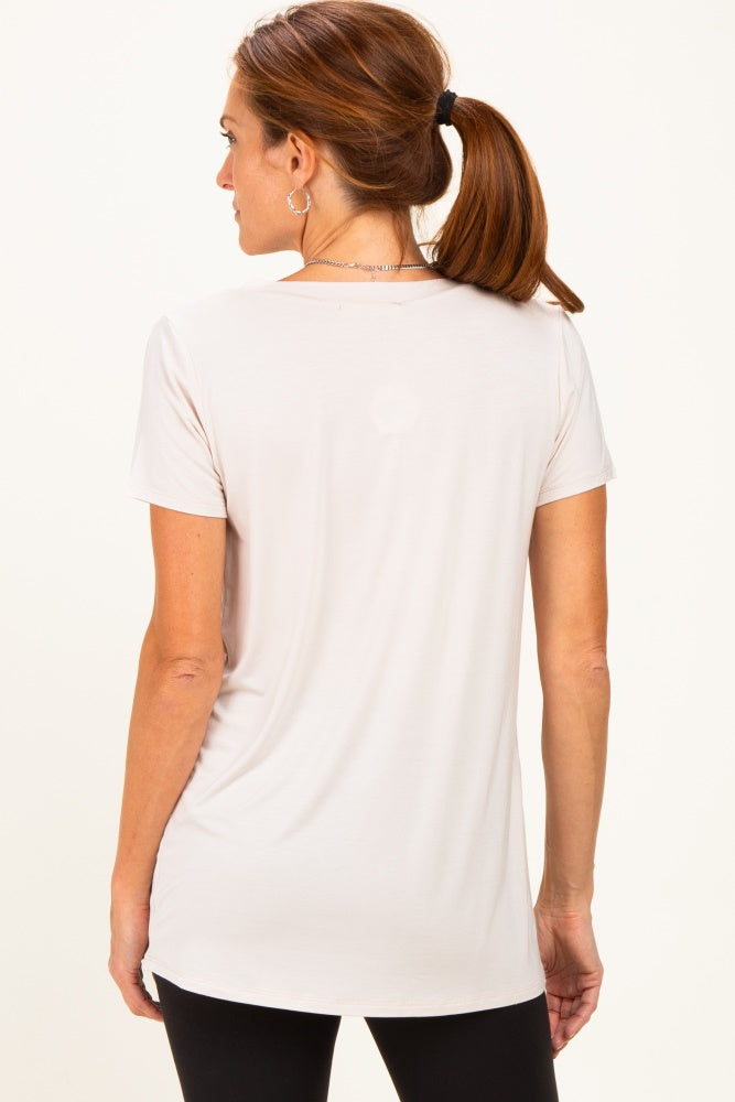 woman wearing a light beige short sleeve top with a rounded hem, shown from the back with a ponytail hairstyle