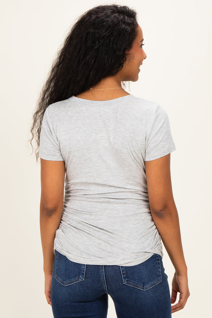 woman wearing a light gray short sleeve maternity top with gathered side details, showing her back
