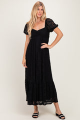 woman wearing a black lace maxi dress with puff sleeves and a tiered hem