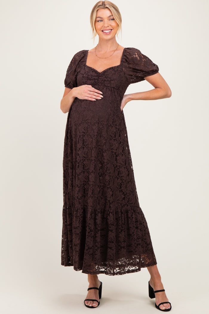 woman wearing a brown lace maternity maxi dress with puff sleeves and a baby bump