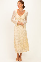 woman wearing a cream lace long sleeve maxi dress with a tie front detail and bell sleeves