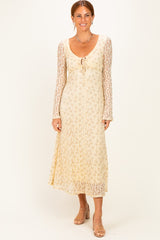 woman wearing a beige floral lace maxi dress with long sleeves and a tie front detail