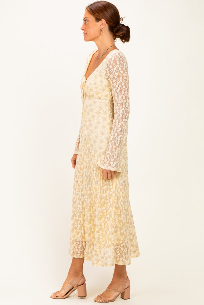 woman wearing a long sleeve cream floral midi dress with a tie detail at the neckline and flared sleeves