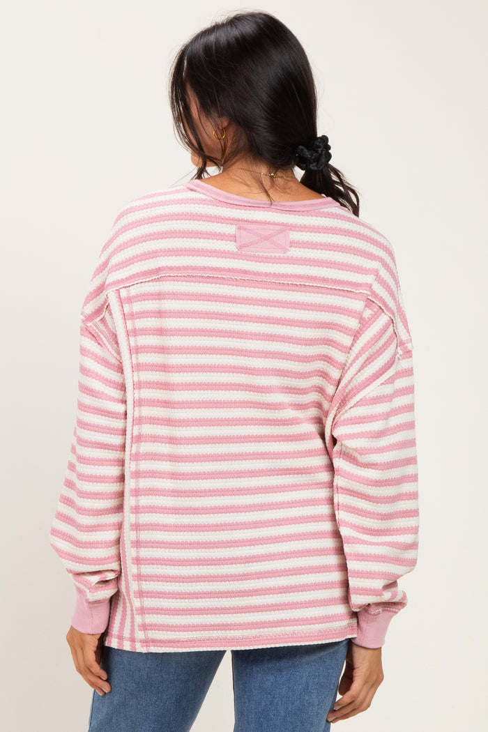 woman wearing a pink and white striped oversized sweater with long sleeves, seen from the back