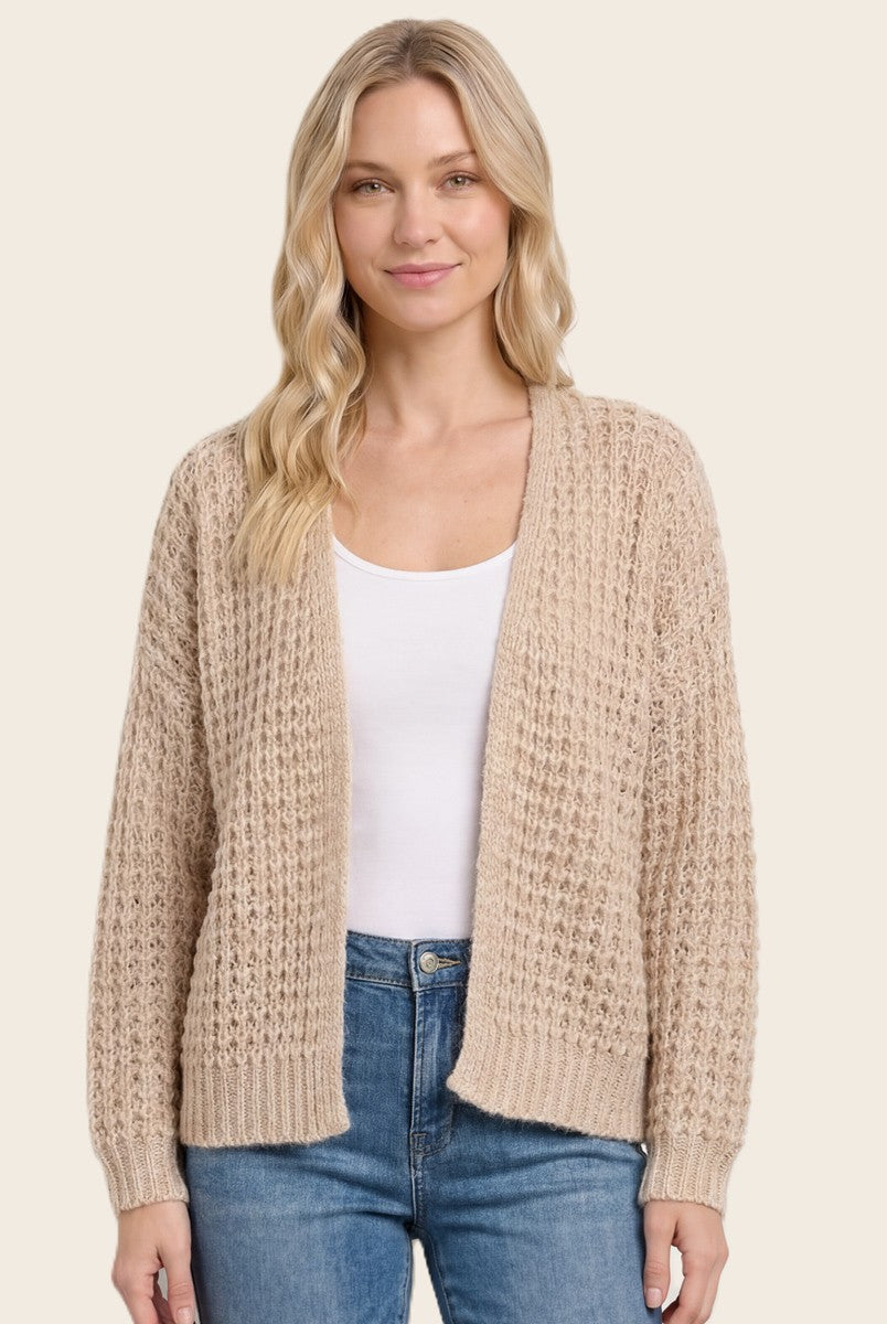 woman wearing a beige knitted cardigan over a white top and blue jeans