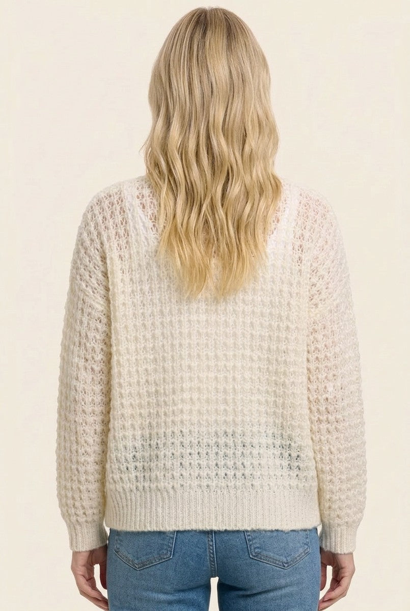 woman wearing a cream textured sweater with a loose fit and long sleeves, viewed from the back