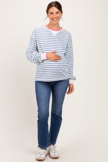 woman wearing a blue and white striped maternity sweatshirt with pink accents and holding her baby bump