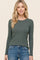woman wearing a green long sleeve ribbed top with a round neckline and casual jeans