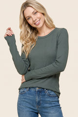 woman wearing a green long sleeve ribbed top with a scoop neckline and smiling