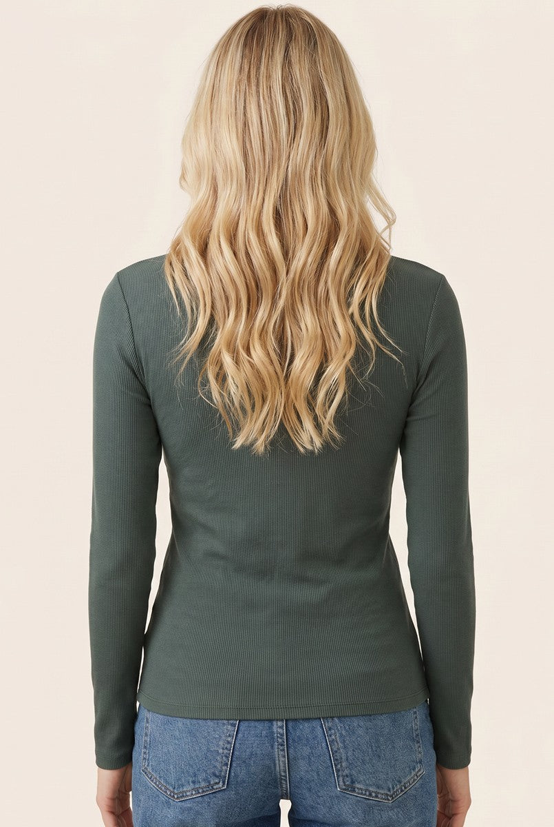 woman wearing a dark green long sleeve fitted top, view from the back with wavy blonde hair and blue jeans