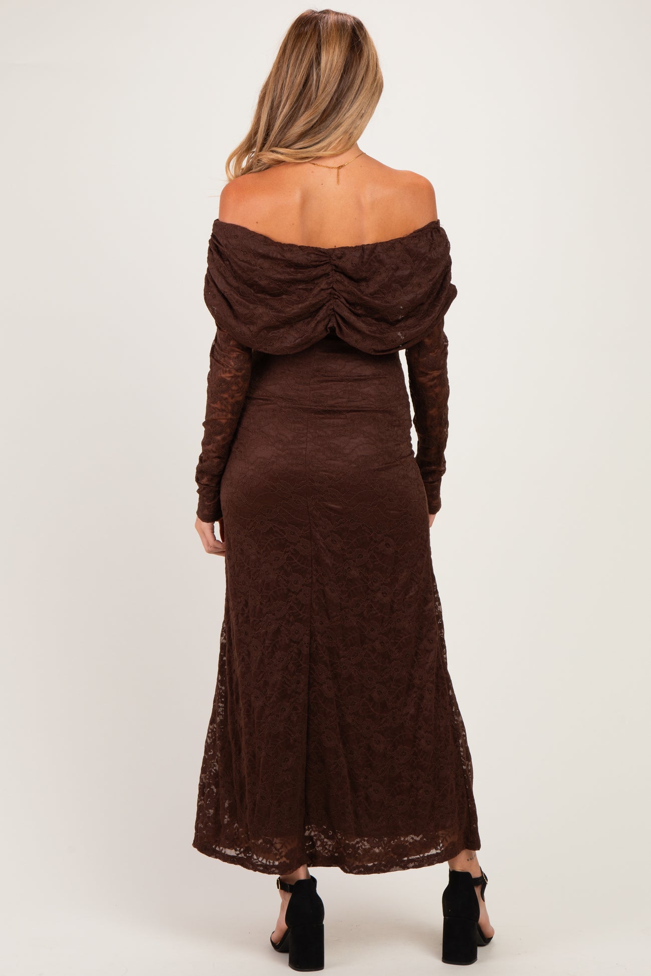 woman wearing a brown off-the-shoulder lace maternity dress with a flowing skirt and long sleeves