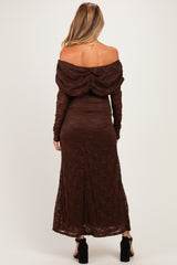 woman wearing a brown off-the-shoulder lace maternity dress with a flowing skirt and long sleeves