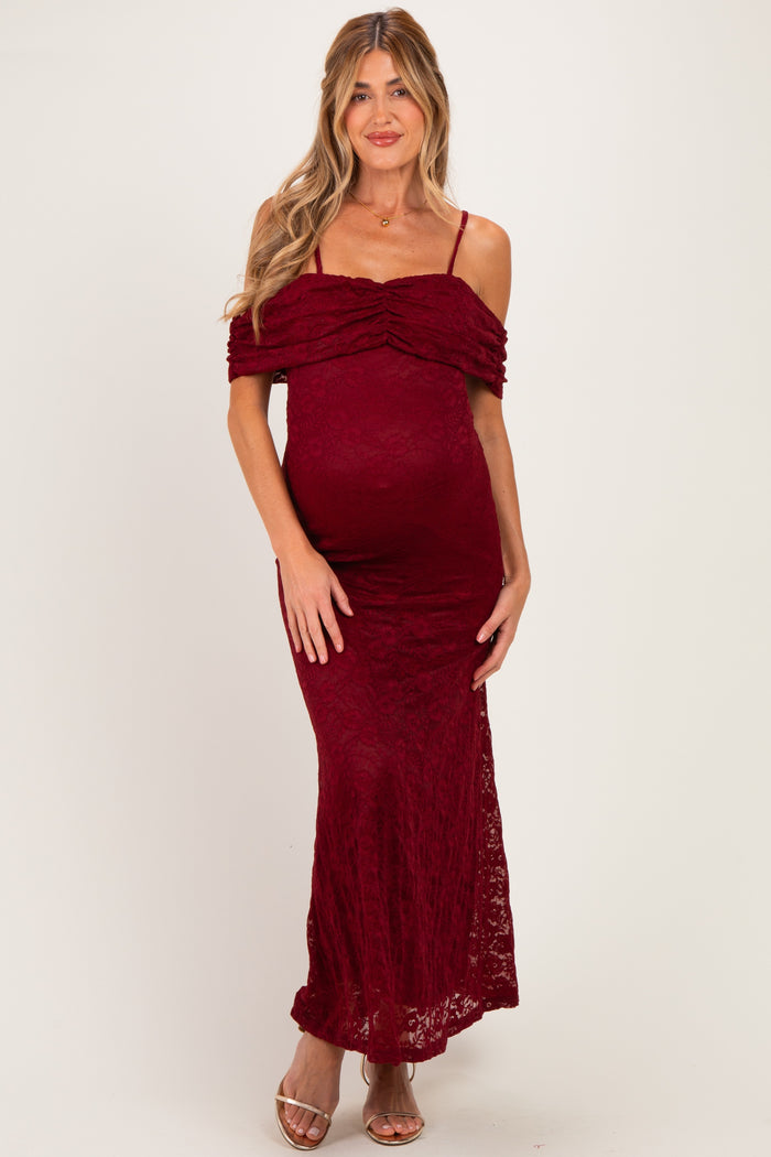 woman wearing a burgundy lace off-the-shoulder maternity dress with a fitted silhouette and a visible baby bump