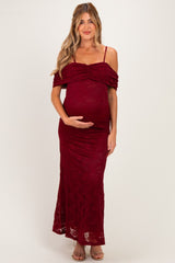 woman wearing a burgundy lace off-the-shoulder maternity dress showing her baby bump