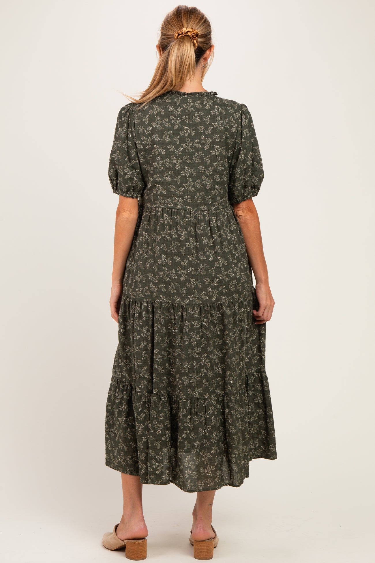woman wearing a dark green floral maternity maxi dress with puff sleeves and tiered skirt, showing her back