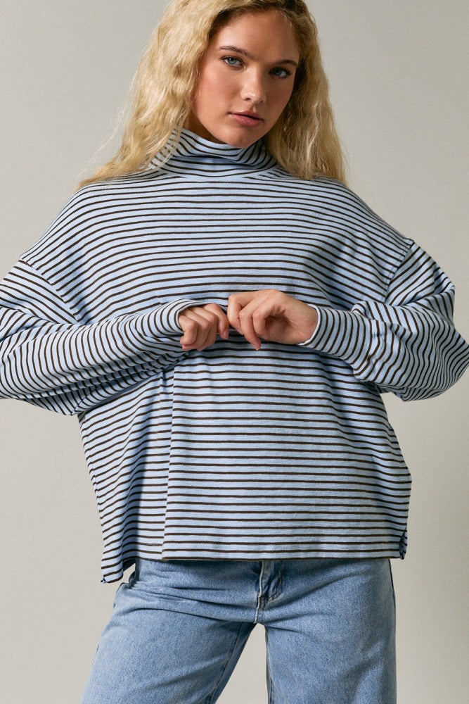 woman wearing a light blue and navy striped turtleneck sweatshirt with oversized sleeves and relaxed fit