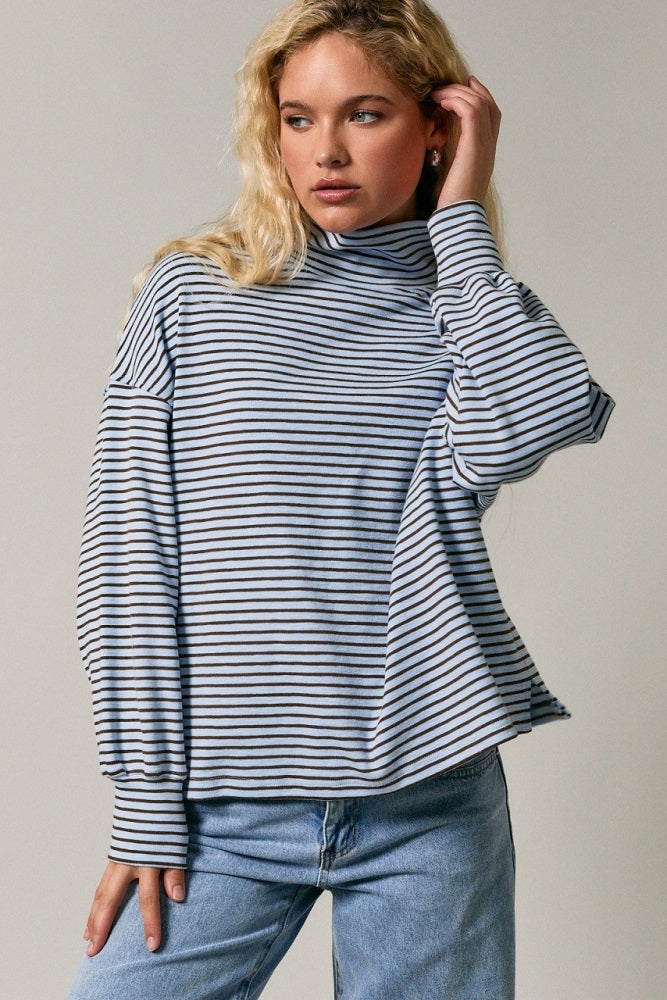 woman wearing a striped long sleeve turtleneck sweater with a relaxed fit and light blue and navy stripes