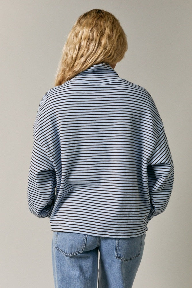 woman wearing a blue and white striped oversized pullover sweater with a mock neck and dropped shoulders