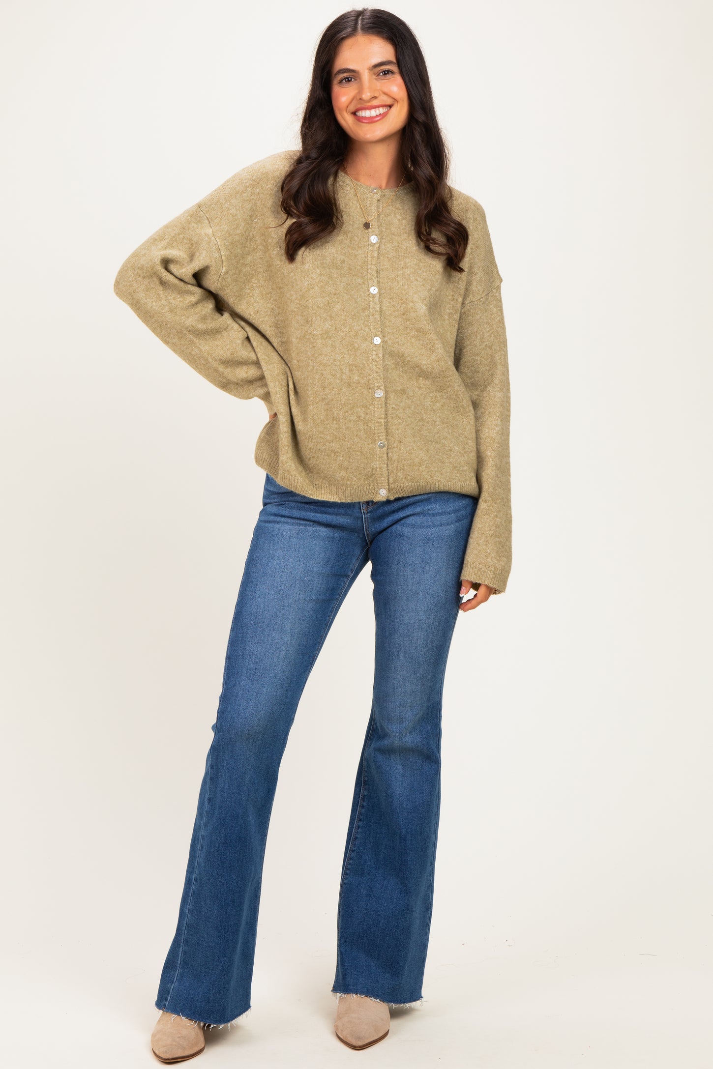 woman wearing a light olive green oversized cardigan with buttons paired with flared blue jeans