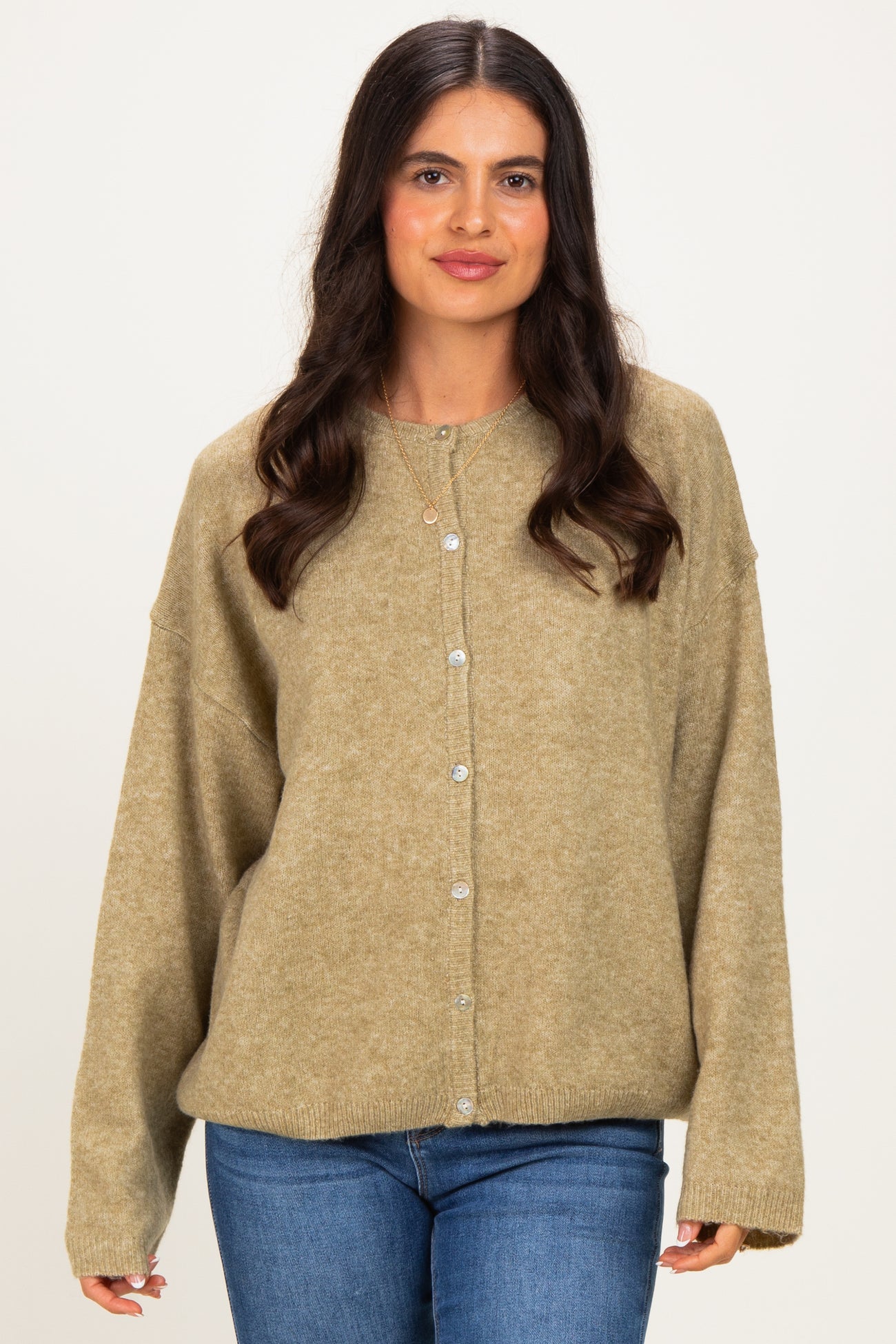 woman wearing a loose-fitting olive green cardigan with buttons and long sleeves, paired with blue jeans