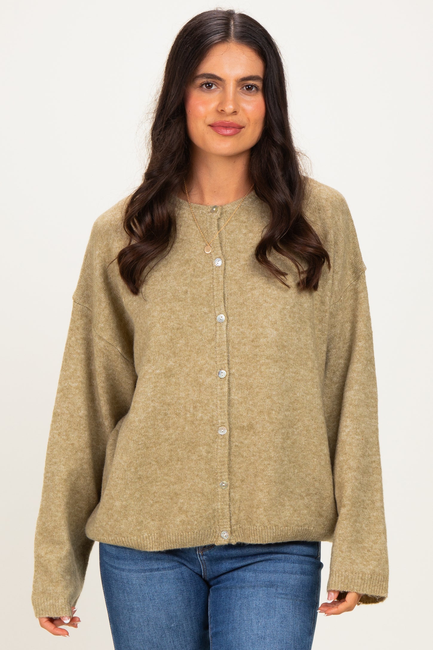 woman wearing a loose-fitting olive green cardigan with buttons and long sleeves, paired with blue jeans