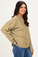 woman wearing a light olive green oversized cardigan with button details and blue jeans